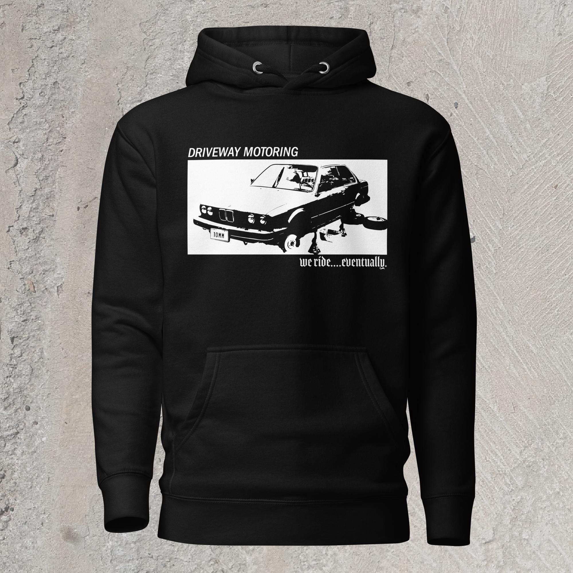 10mm funny graphic black hoodie sweatshirt with BMW car on jack stands with text "Driveway motoring. We ride...eventually"