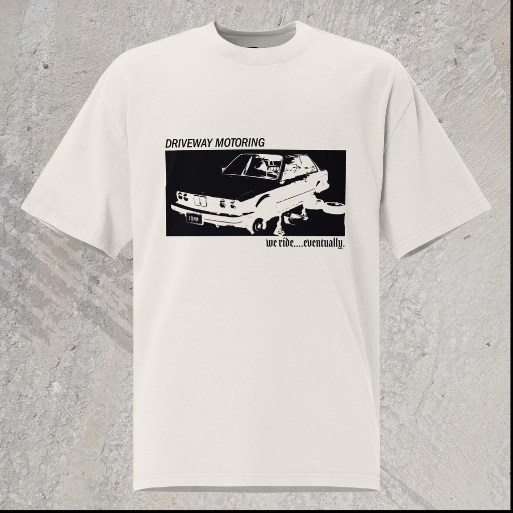 10mm funny graphic white oversized T-shirt with BMW car on jack stands with text "Driveway motoring. We ride...eventually"