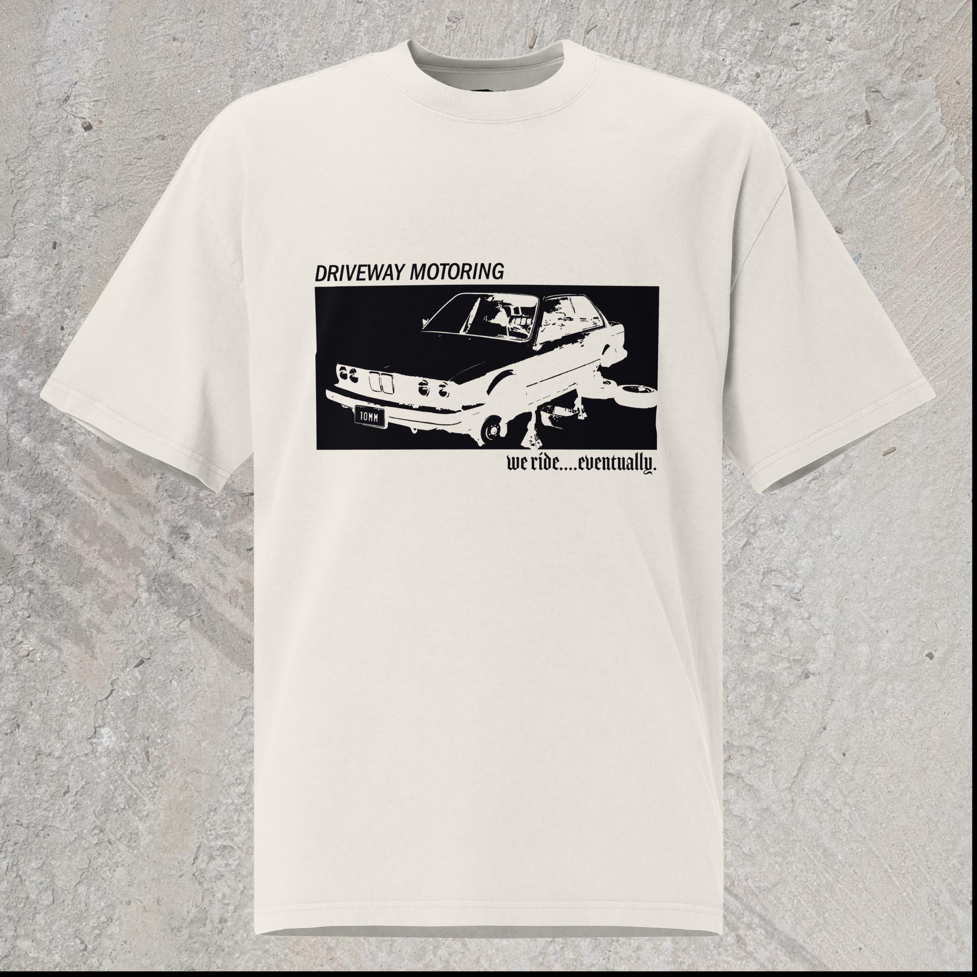 10mm funny graphic white oversized T-shirt with BMW car on jack stands with text "Driveway motoring. We ride...eventually"