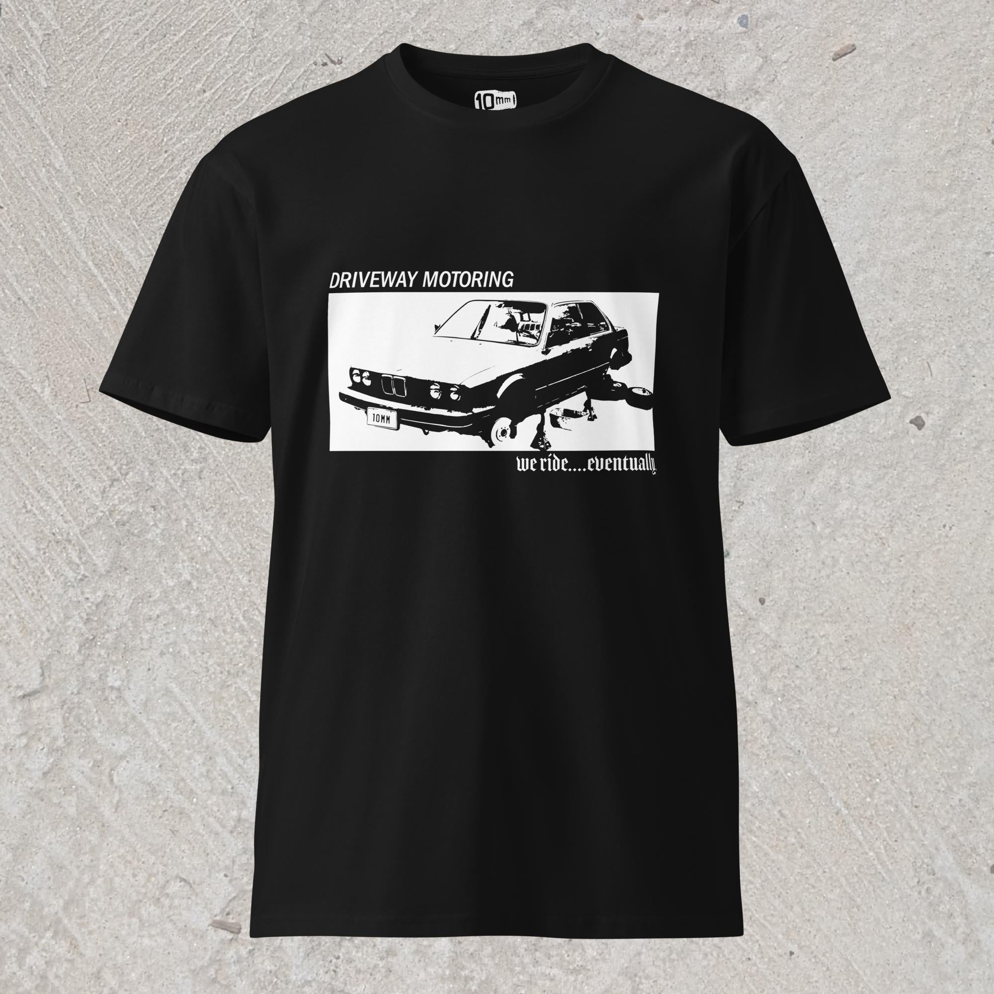 10mm funny graphic black T-shirt with BMW car on jack stands with text "Driveway motoring. We ride...eventually"