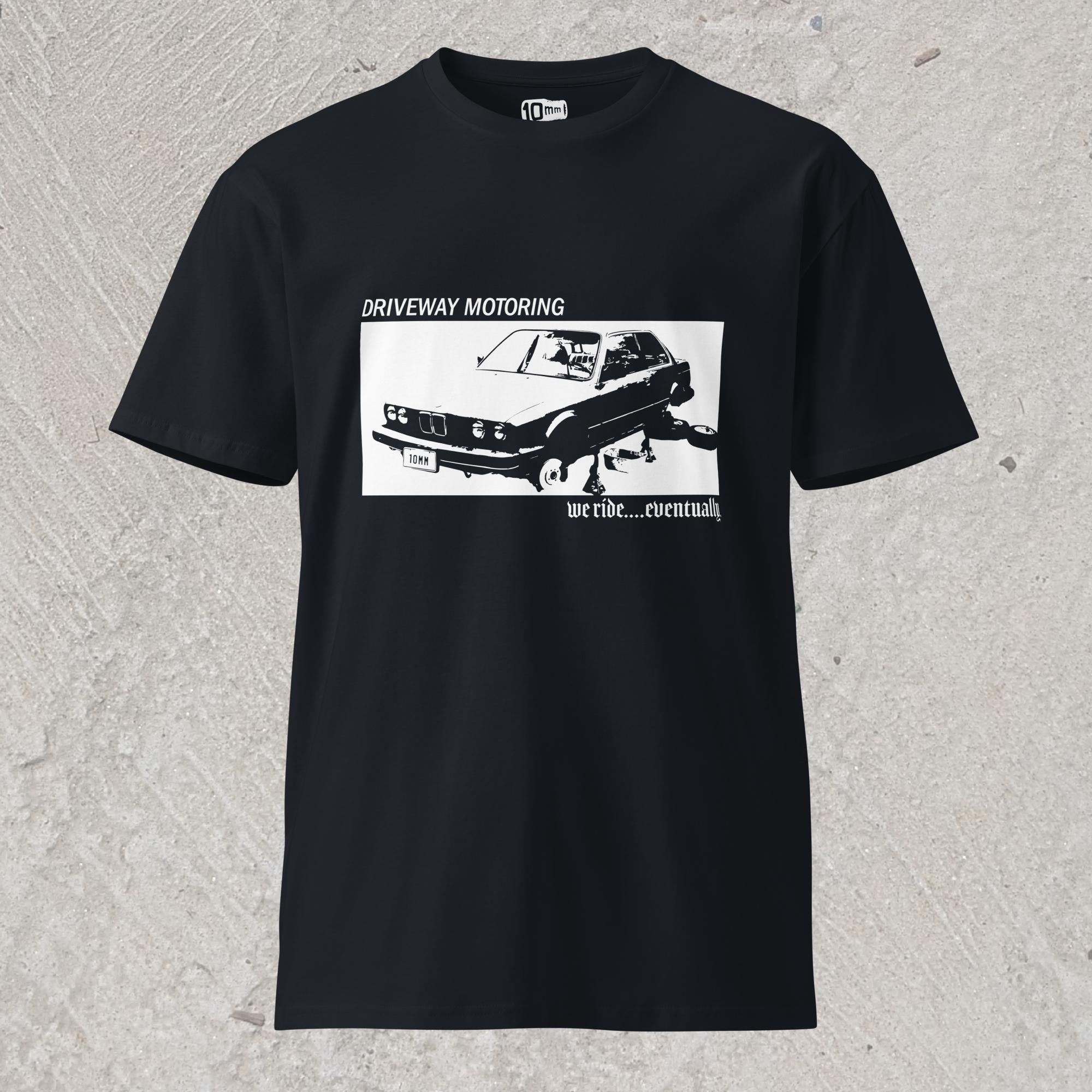 10mm funny graphic navy blue T-shirt with BMW car on jack stands with text "Driveway motoring. We ride...eventually"