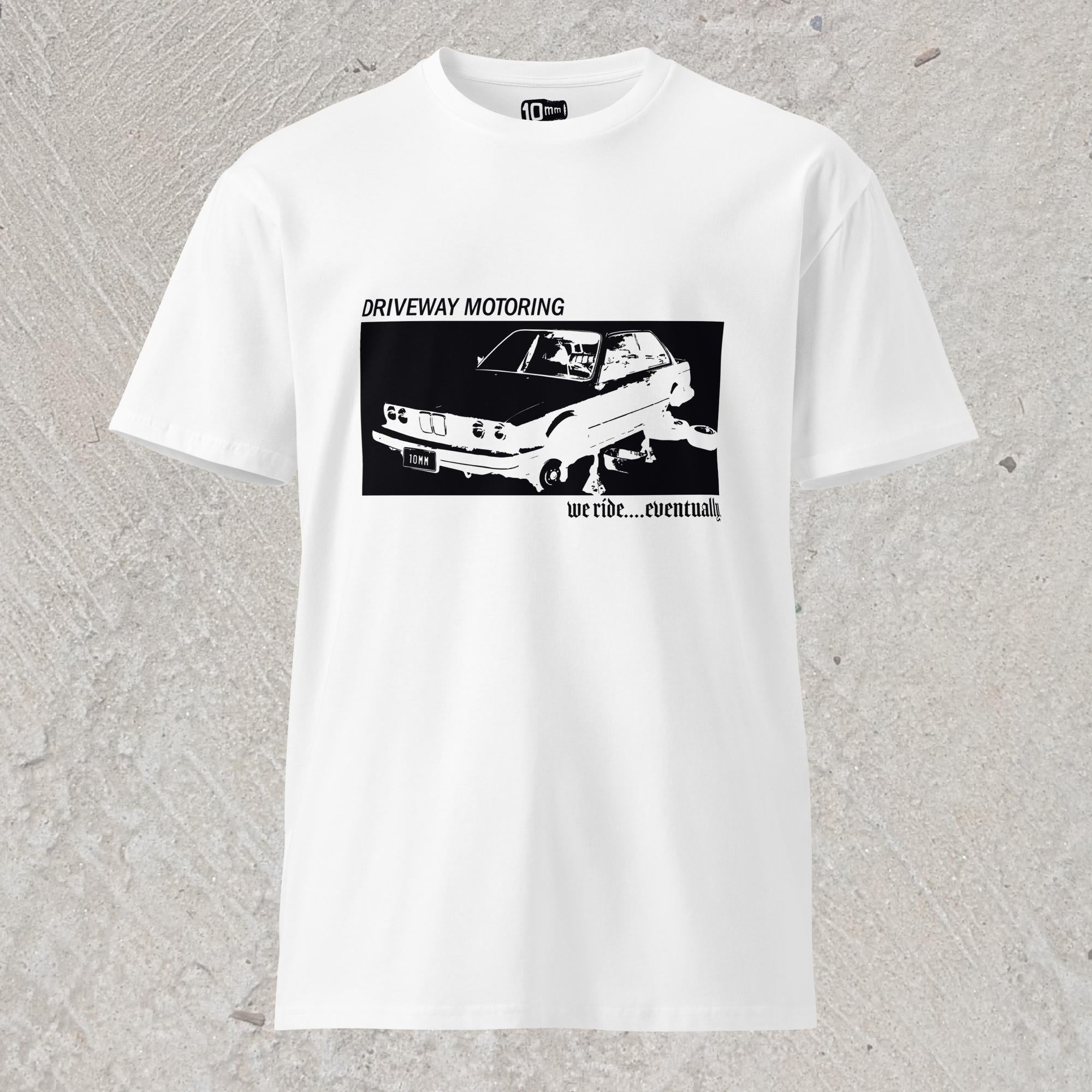 10mm funny graphic white T-shirt with BMW car on jack stands with text "Driveway motoring. We ride...eventually"