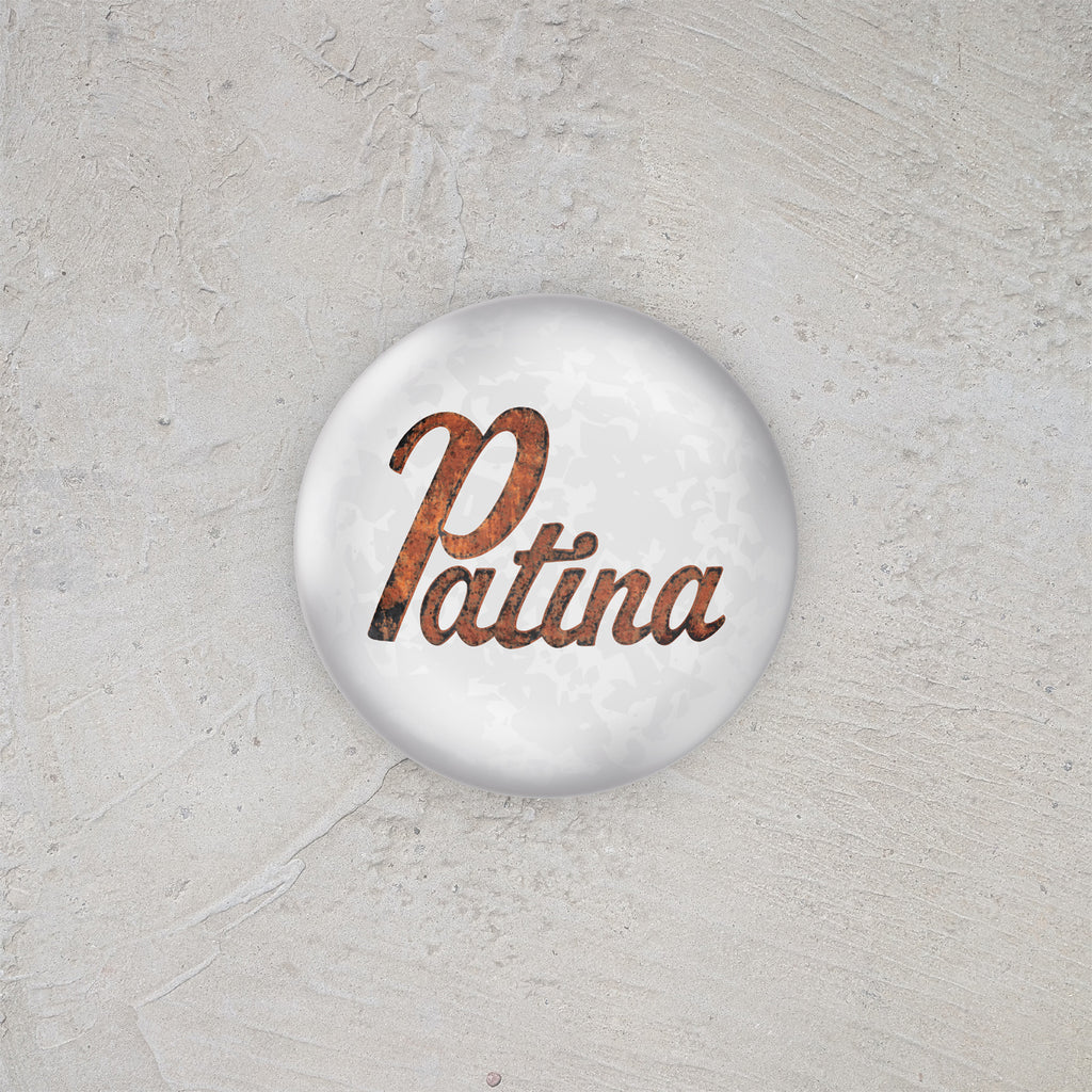 Button badge with 'Patina' text on a textured gray background