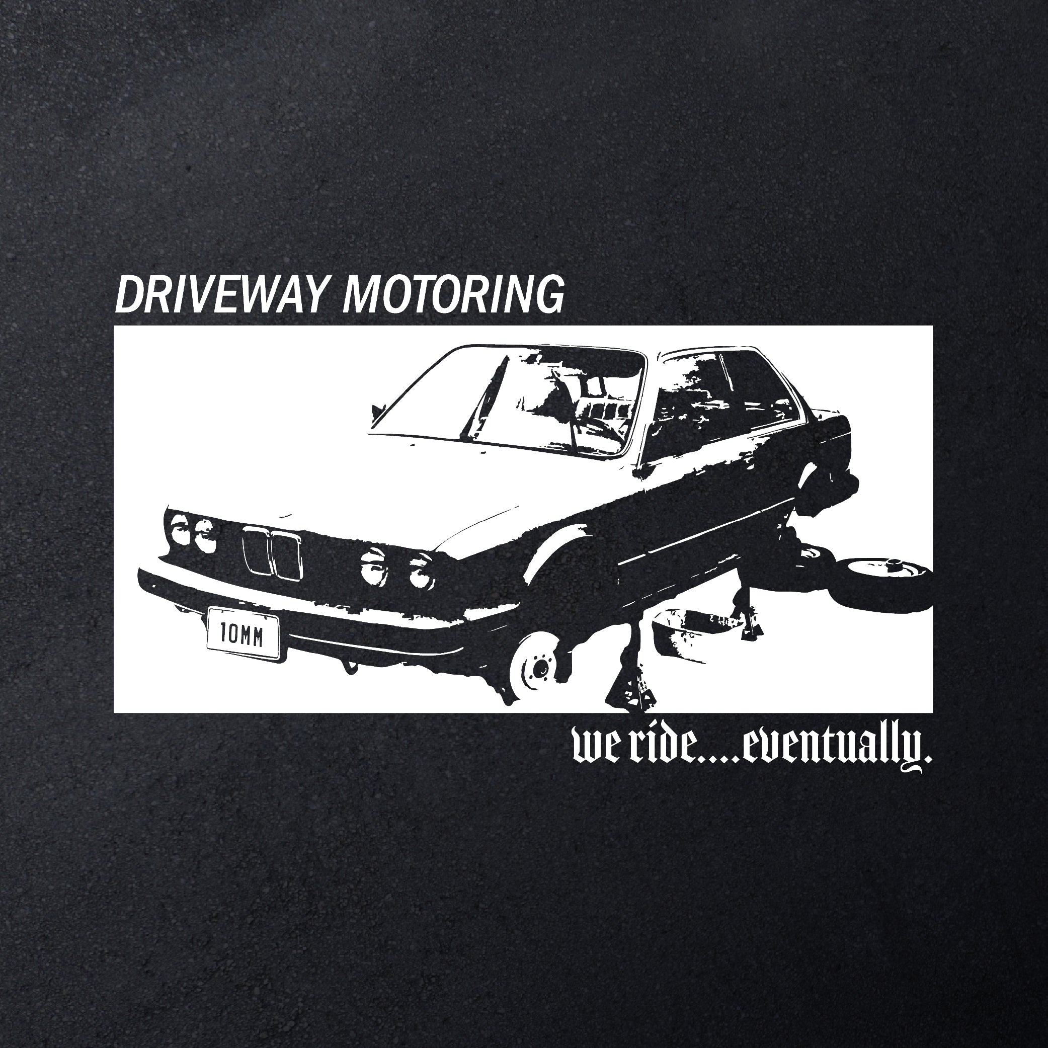 Black t-shirt with white graphic of a BMW E-30 on jack stands and text 'Driveway Motoring' and 'we ride...eventually'.